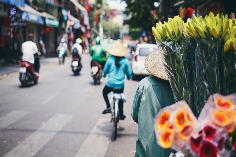 Vietnamese street scene. Womena nd men riding bicycles and motorbikes