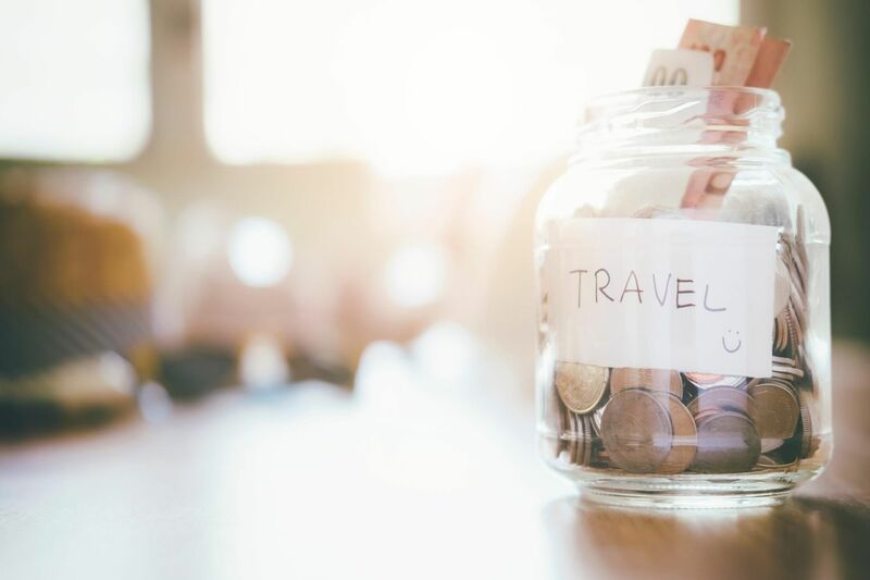 a glass jar sitting on a table full of money labelled travel