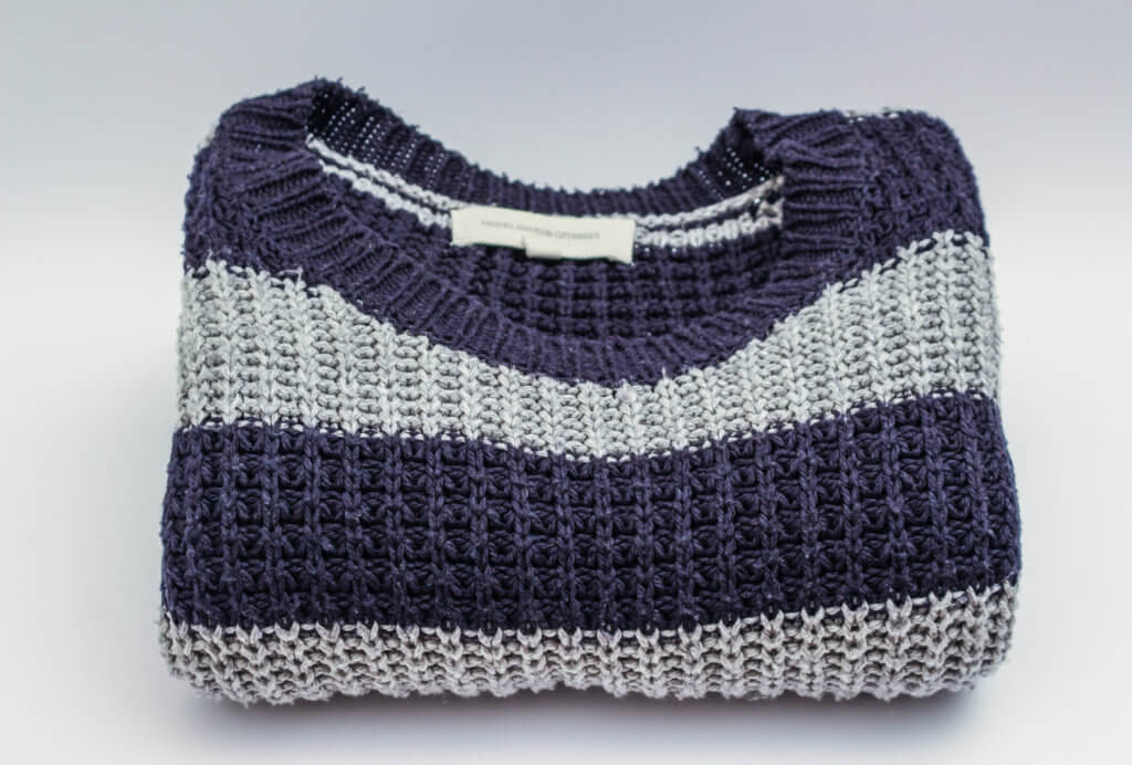 a navy blue and grey striped sweater folded neatly