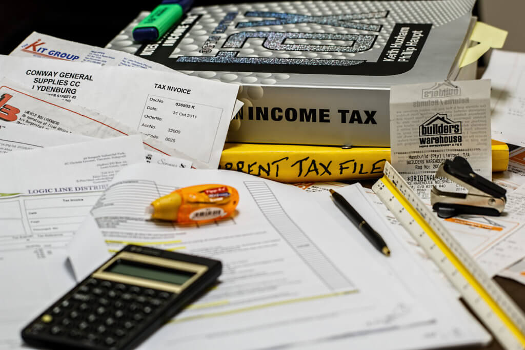 pile of paper work, tax text books, calculator, pens and rulers