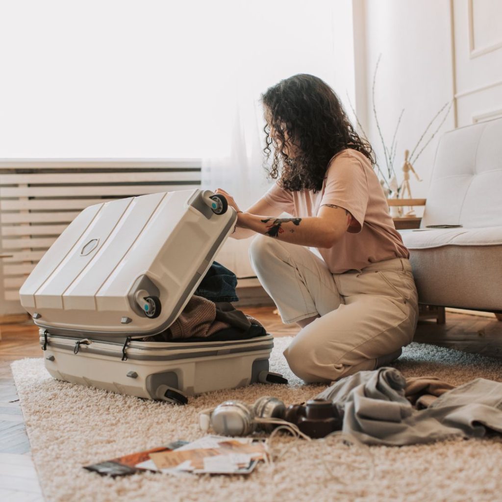 solo traveller packing her suitcase in hostel dorm room