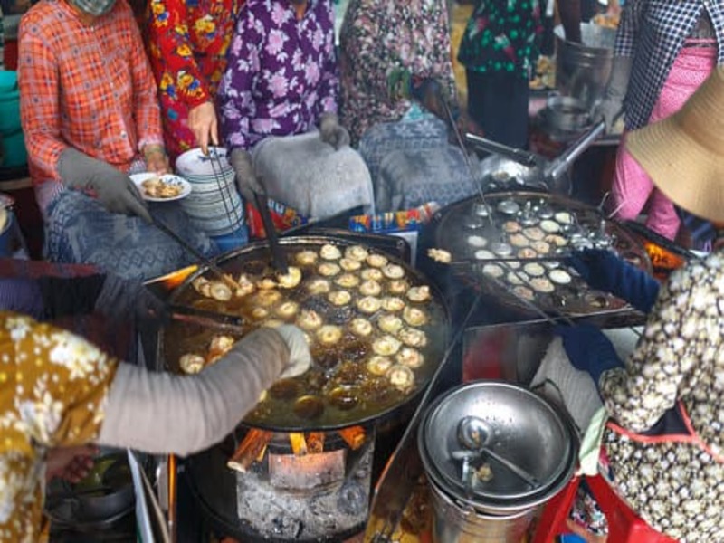 eight people sitting beside two big cookers, cooking street food ready to sell