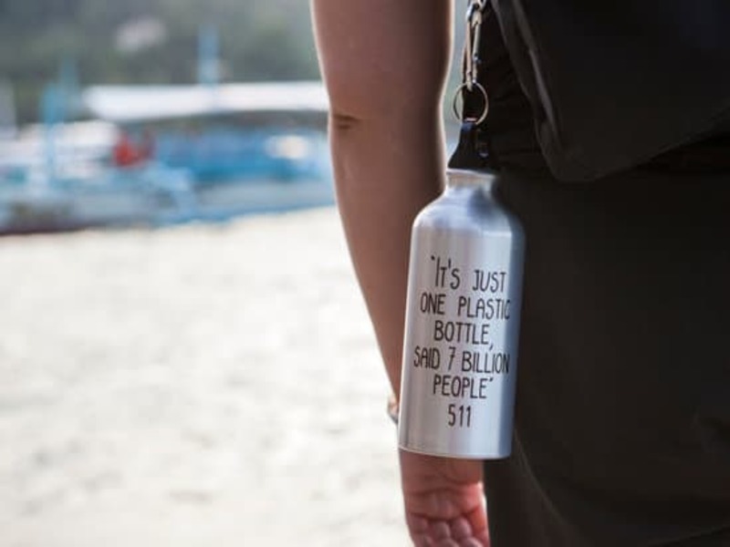 Reusable water bottle hanging from a travellers backpack