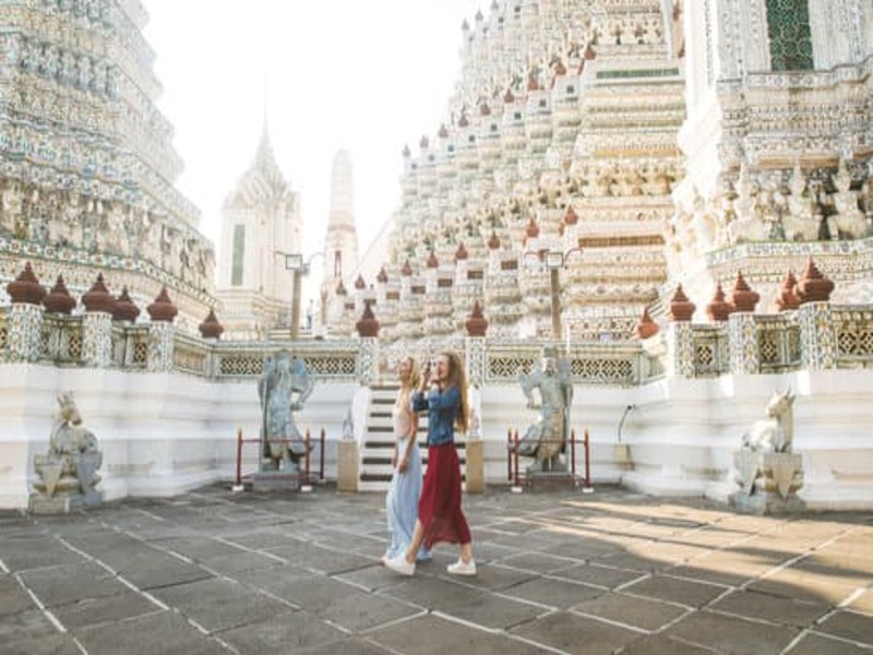 two female tourists visiting a Southeast Asian temple wearing culturally appropriate clothing