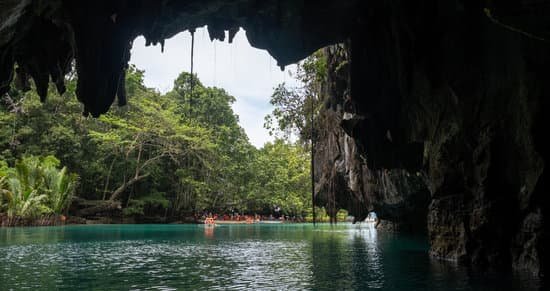 a view looking out from inside one of the caves. there are orange kayaks out in the open with people enjoying the scenery