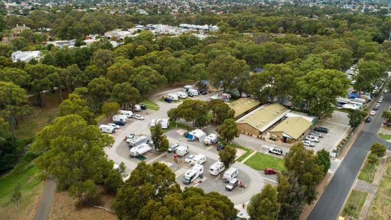 aerial view of Windsor Gardens caravan park in the suburbs of Adelaide. the image shows caravans and cars parked at the sites and surrounded by beautiful green shady trees