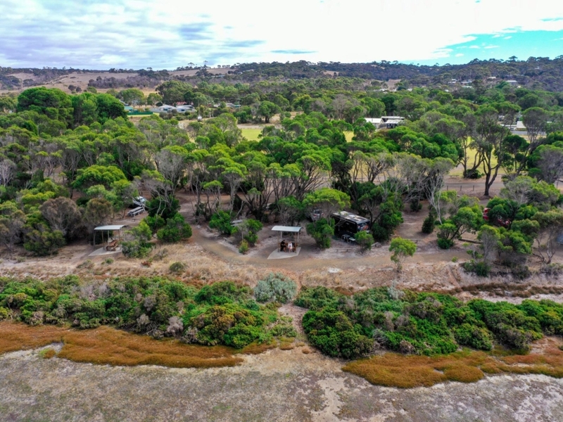 An aerial image of American River camping ground on Kangaroo Island. There is thick bushland and a view of teh campsites visible through some of the trees