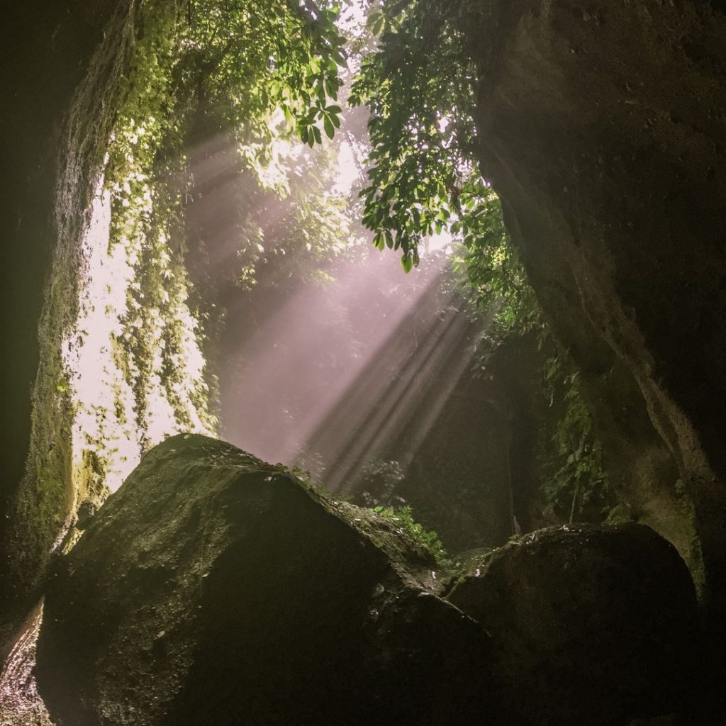 sun rays streaming through the roof of the canyon at Tukad Cepung Waterfall