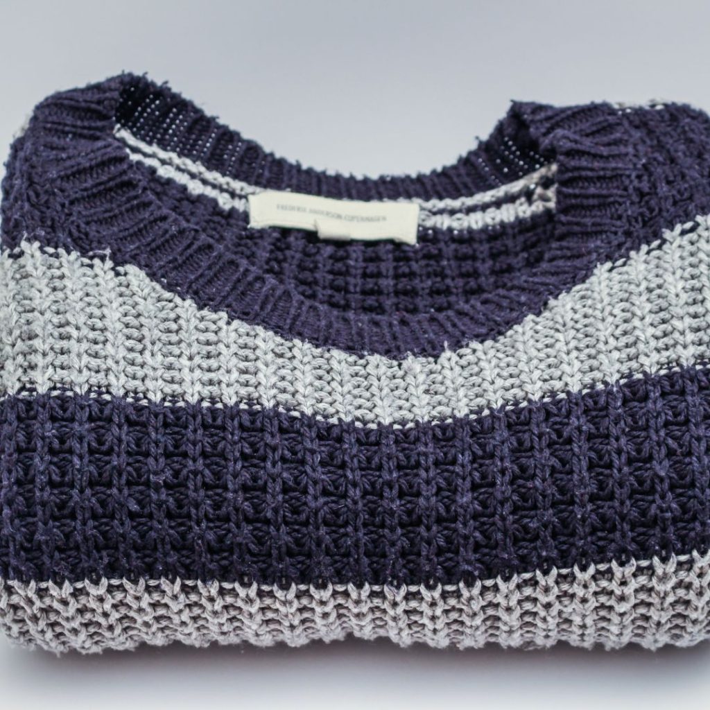 a bulky woollen blue and white striped jumper folded neatly with the tag showing