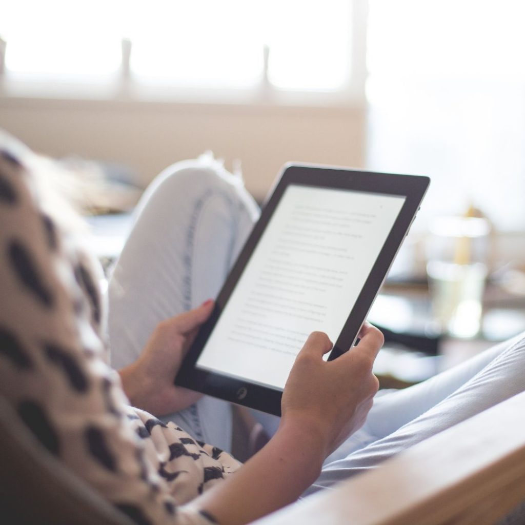 a woman in a hostel dorm room with her reading essential Kindle