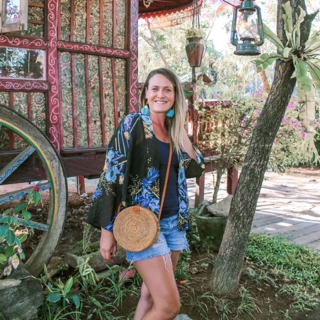 Luisa is a solo traveller in Bali standing under a tree with a lantern hanging from a branch